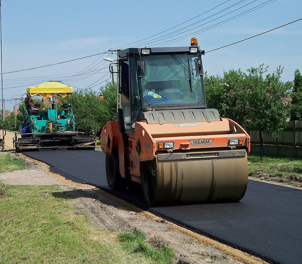 Lucrări de construcție a unui drum, cu utilaje și muncitori, ilustrativ pentru șantierele rutiere din Centura Bucureștiului.