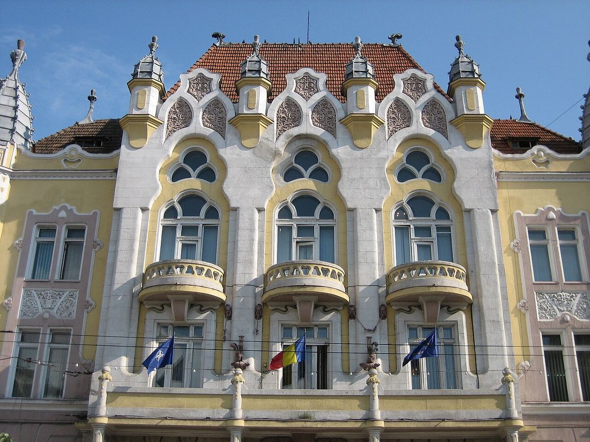 Fațada Palatului Administrativ din Cluj-Napoca, sediul Prefecturii Cluj, cu steagul României și steaguri ale UE.