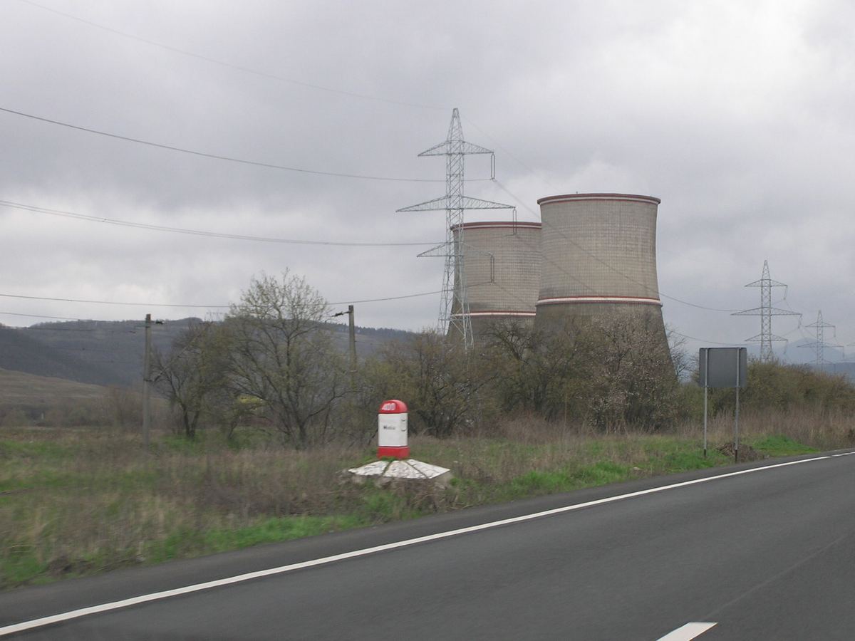 Vedere a unei centrale electrice industriale, fotografiată de pe un drum, imagine ilustrativă.