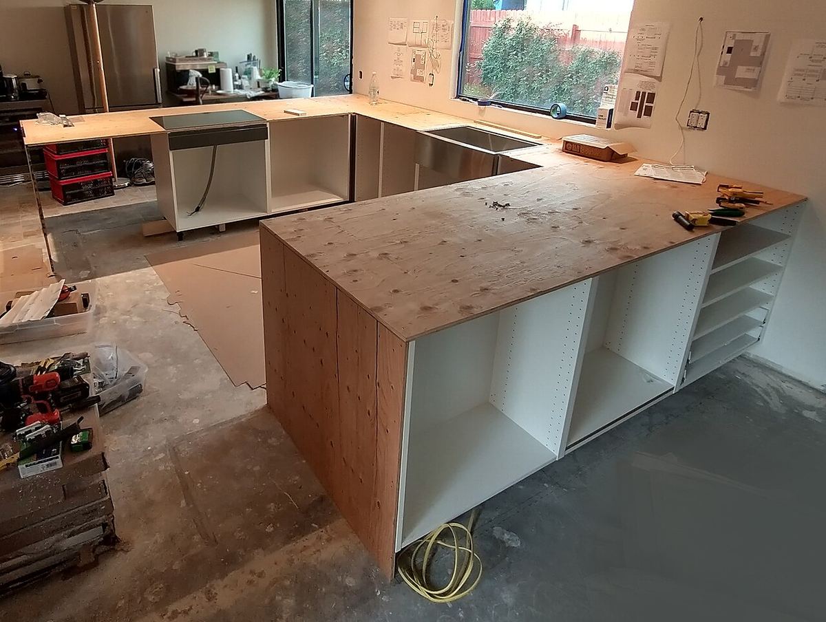 Strat de placaj din lemn instalat pe o structură de bucătărie, înainte de montarea blatului final.