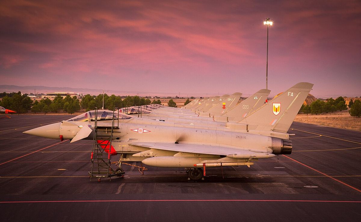 Avioane de luptă Typhoon ale Forțelor Aeriene Regale parcate pe platforma unei baze aeriene, la apus (fotografie de arhivă).