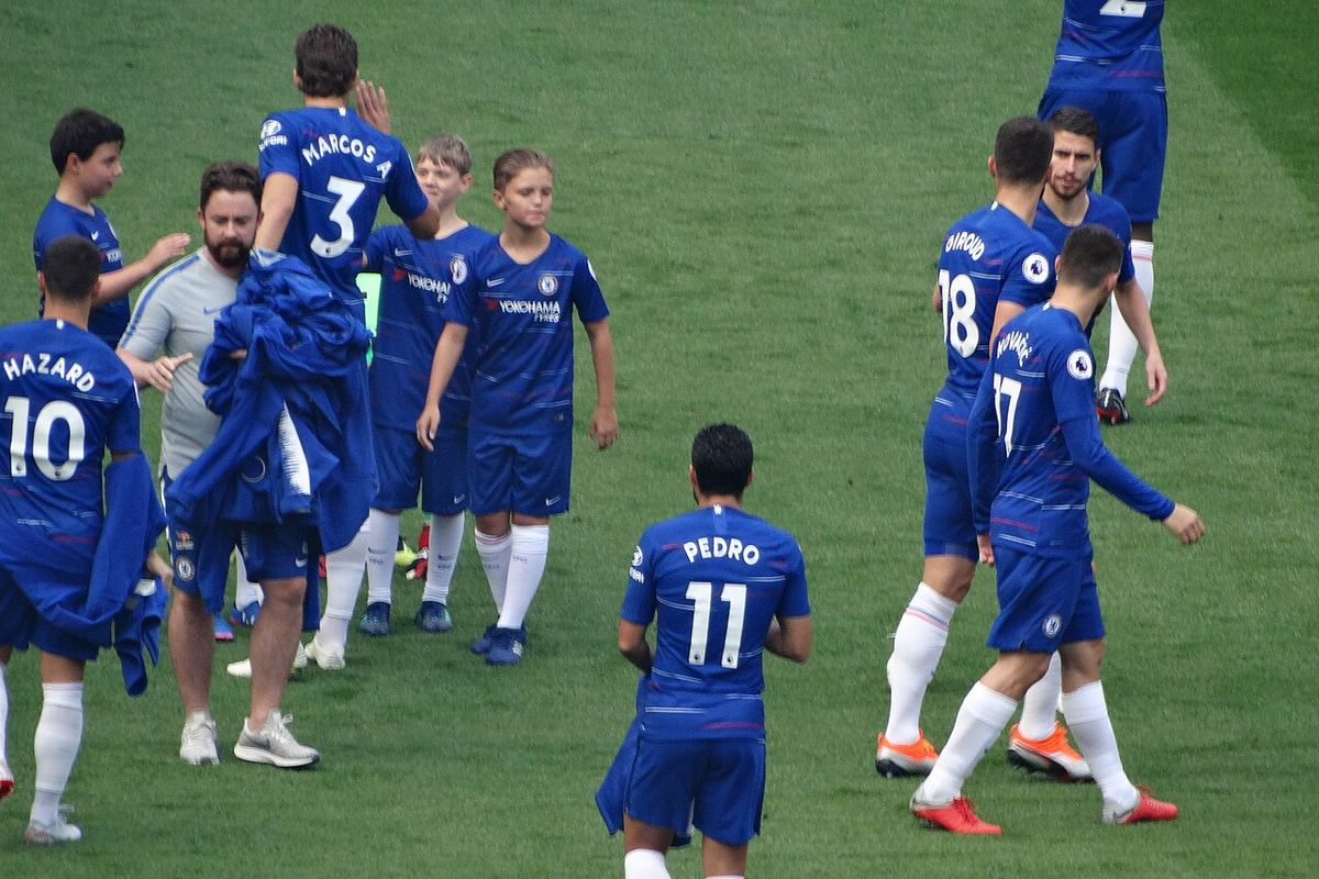 Jucători de fotbal pe teren în timpul unui meci, fotografie ilustrativă cu echipamente sportive și gazon verde.