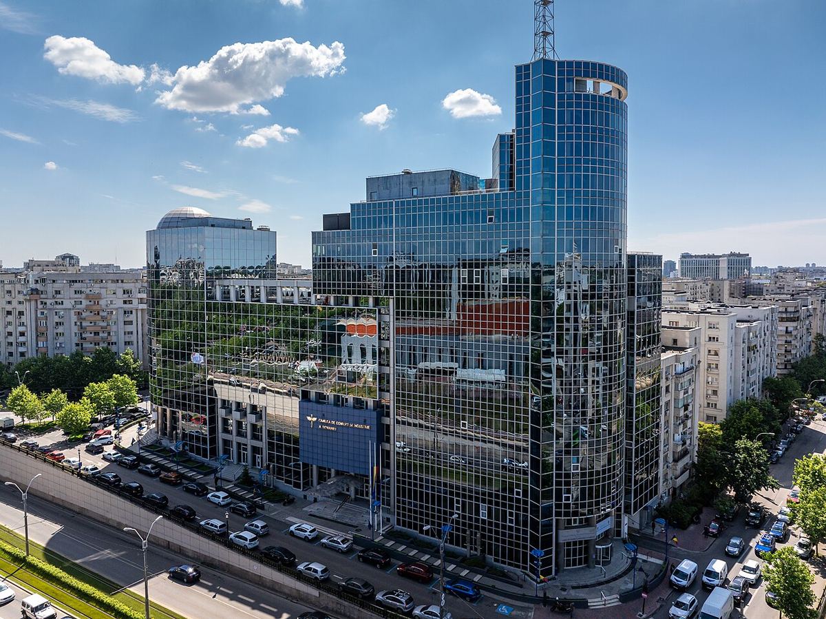 Clădirea-sediu a CCIR din București, cu fațadă de sticlă, fotografiată din înălțime, lângă un bulevard aglomerat.