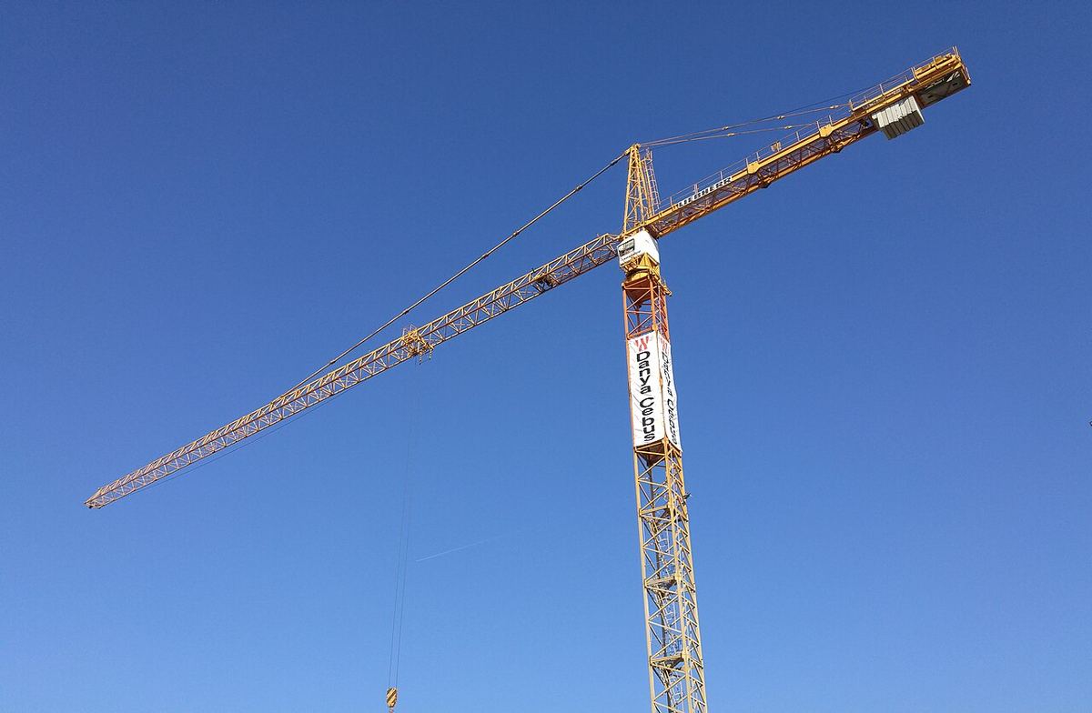 Macara de construcție înaltă și suplă, conturată pe un cer albastru senin.