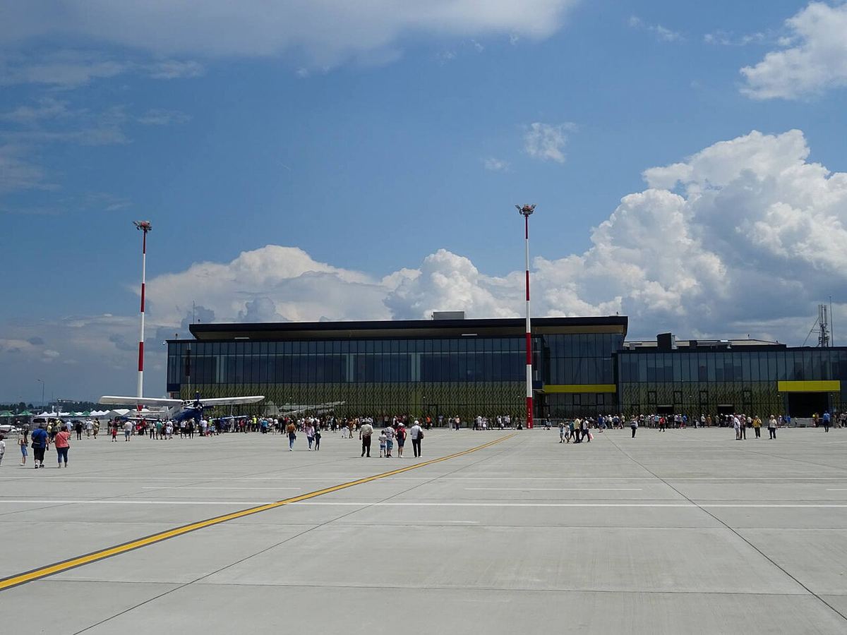 Clădirea terminalului Aeroportului Internațional Brașov-Ghimbav, cu platforma din față și vizitatori pe o zi însorită.