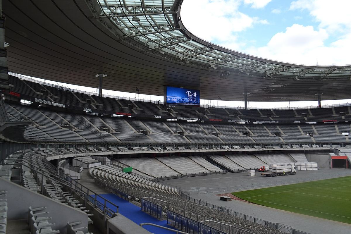 Vedere interioară a stadionului Stade de France din Paris, cu tribune goale și gazonul verde al terenului.