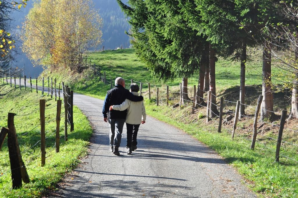 Doi pensionari care se plimbă pe o alee