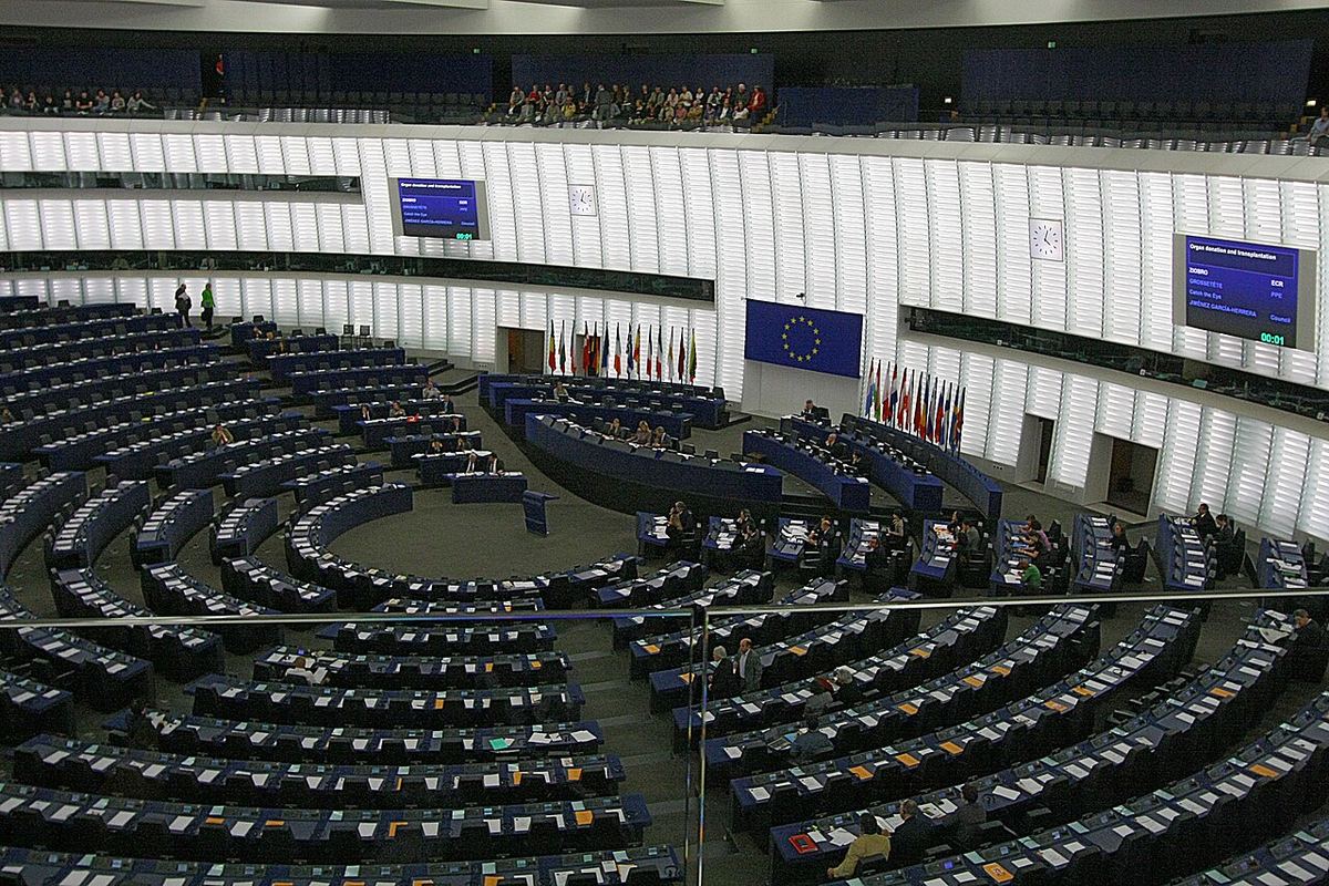 Sala plenară a Parlamentului European din Strasbourg, cu rânduri de bănci și steagul UE pe perete.