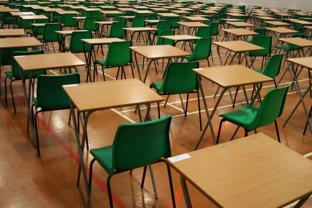Sală pregătită pentru examen, cu bănci și scaune aliniate