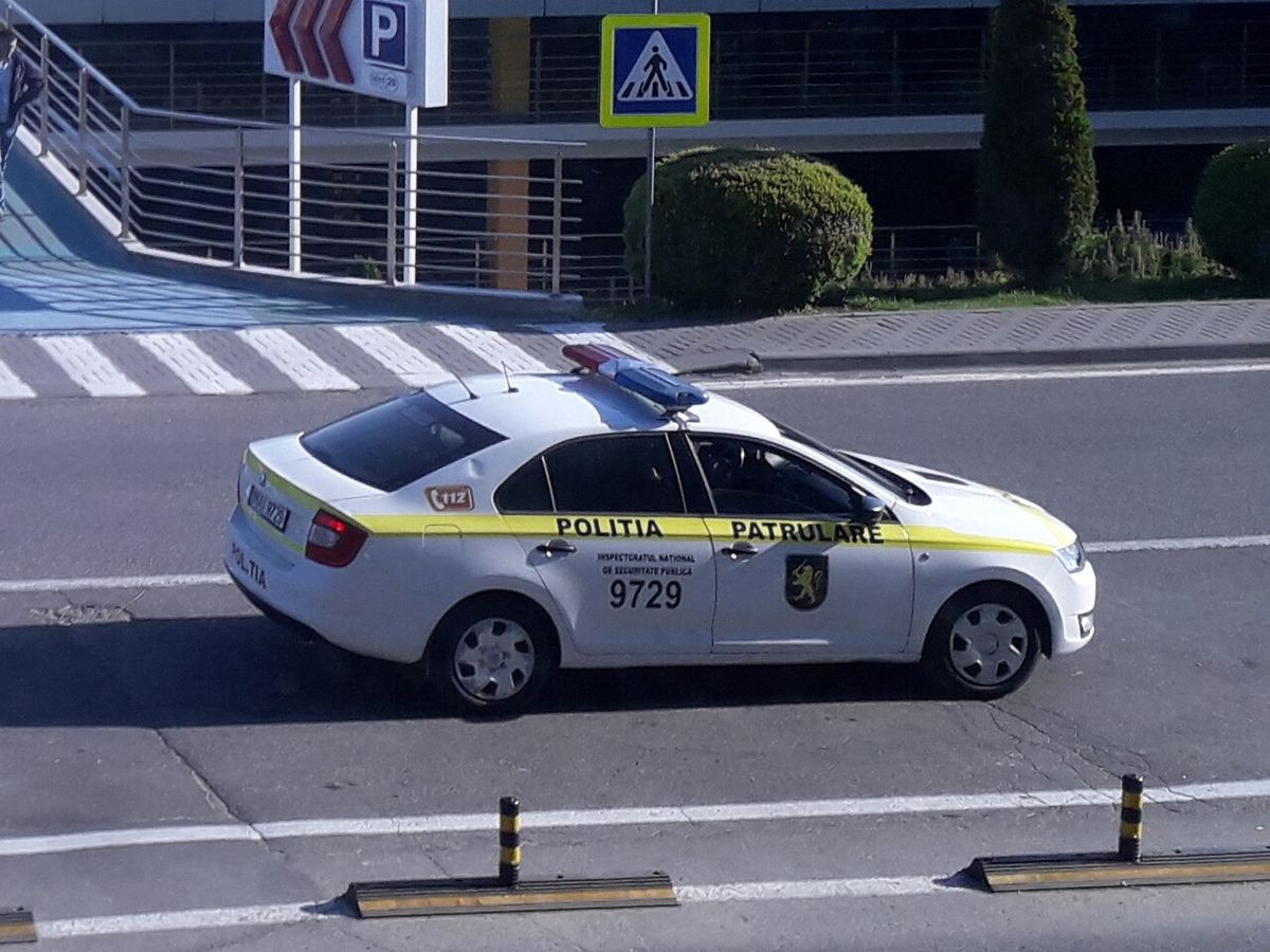 Mașină de patrulare a poliției, alb-galbenă, parcată lângă un aeroport, ilustrație pentru o anchetă privind mobilizarea tinerilor.