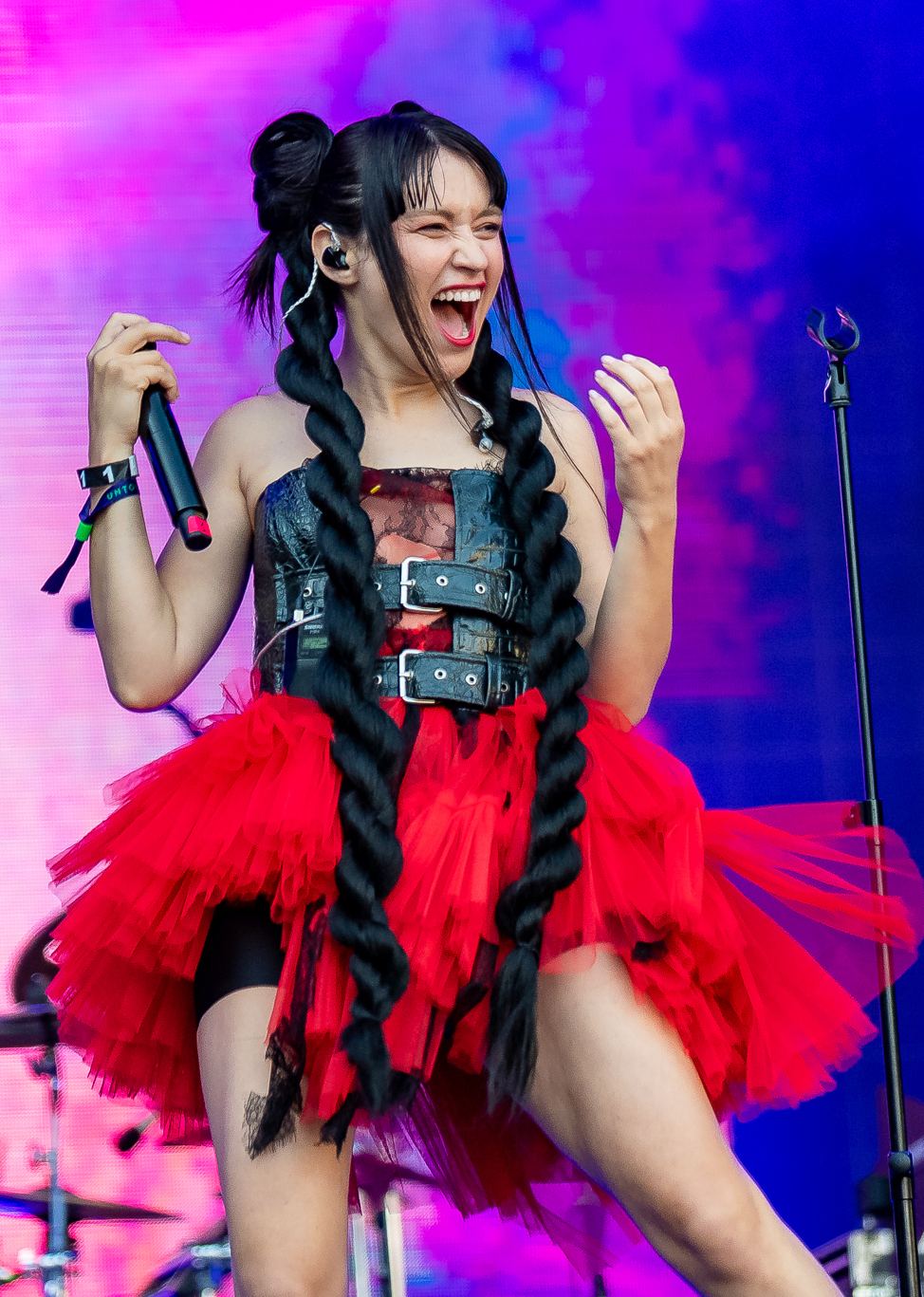 Irina Rimes cântând pe scenă, cu microfon în mână, îmbrăcată în rochie roșie din tul, la festivalul Untold 2023.