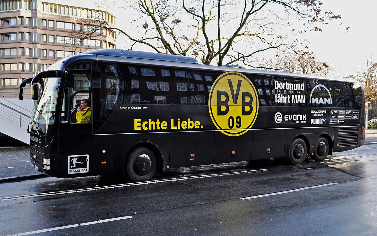 Autocarul echipei Borussia Dortmund, negru, cu emblema BVB 09 și inscripția „Echte Liebe”, pe o stradă din oraș.
