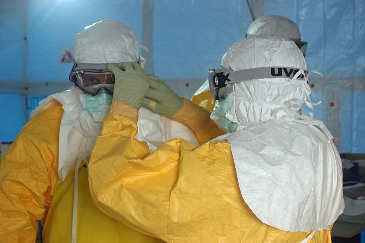 Un membru al personalului leagă masca unui medic înainte de intrarea într-o unitate de tratament pentru Ebola, în Liberia.