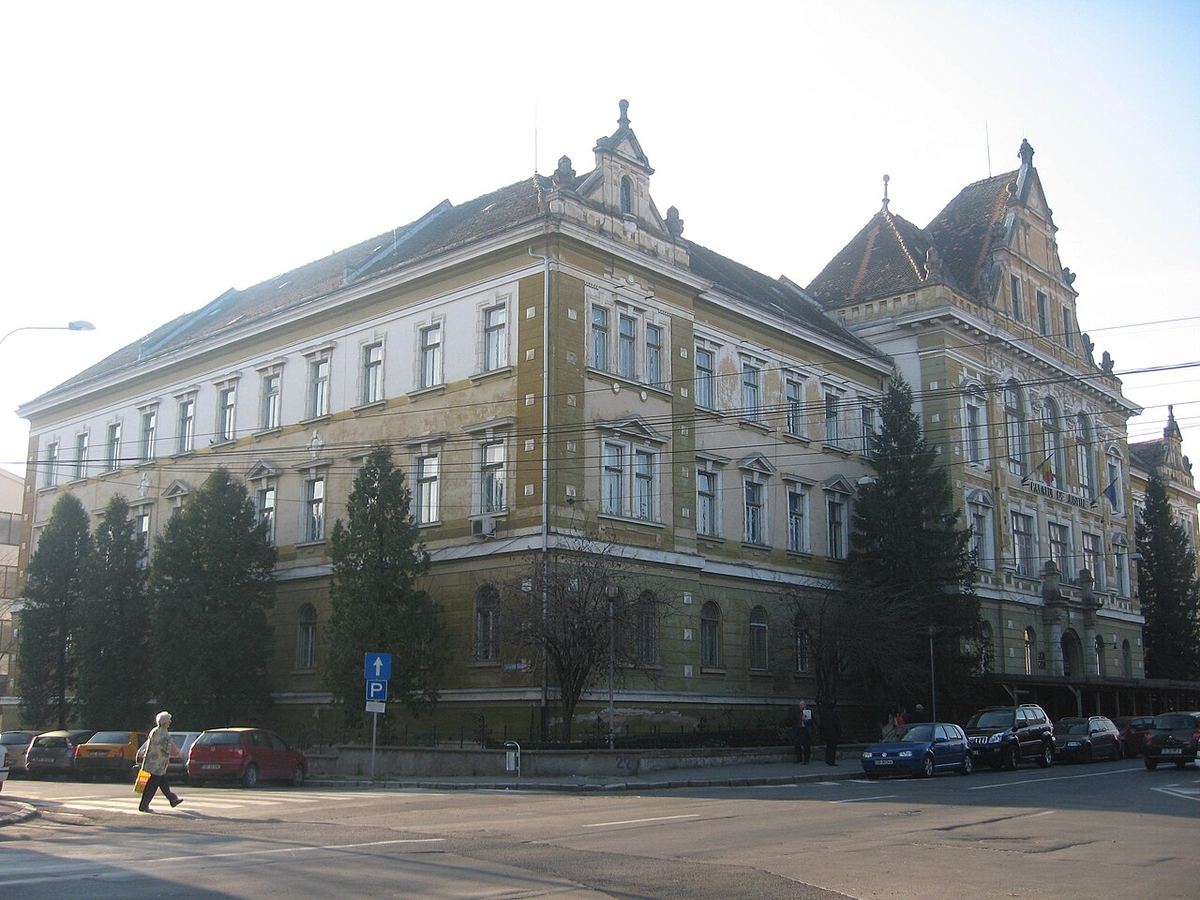 Fațada Palatului de Justiție din Sibiu, clădire istorică galbenă cu acoperiș mansardat, fotografiată pe timp de zi.