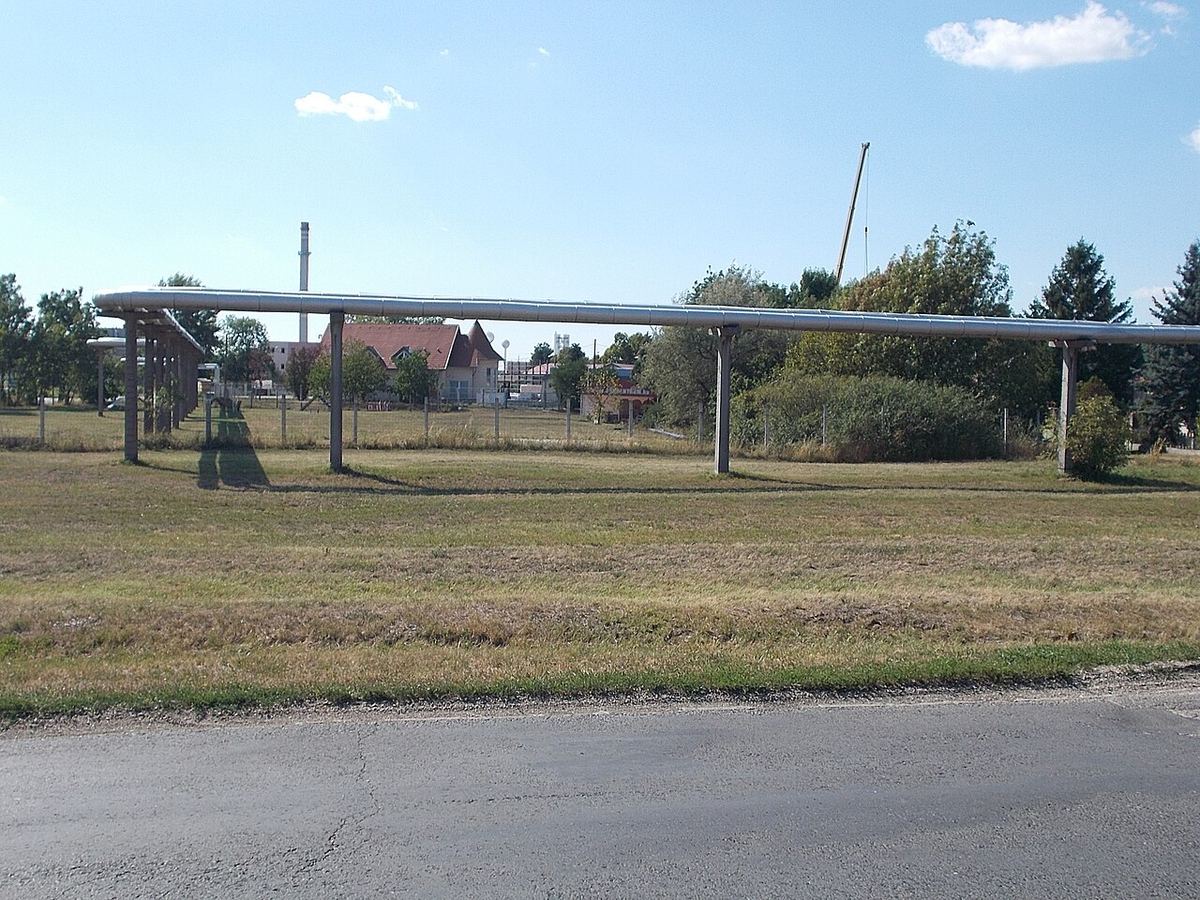 Conductă industrială care traversează o zonă industrială, lângă turnuri metalice, în Mosonmagyaróvár, Ungaria.