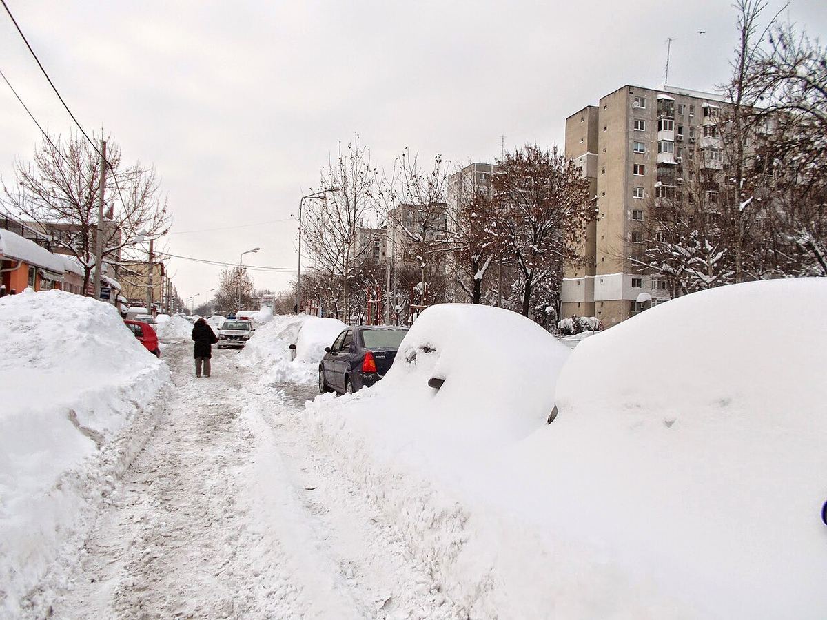 Trotuar cu zăpadă până la genunchi și mașini îngropate în nămeți