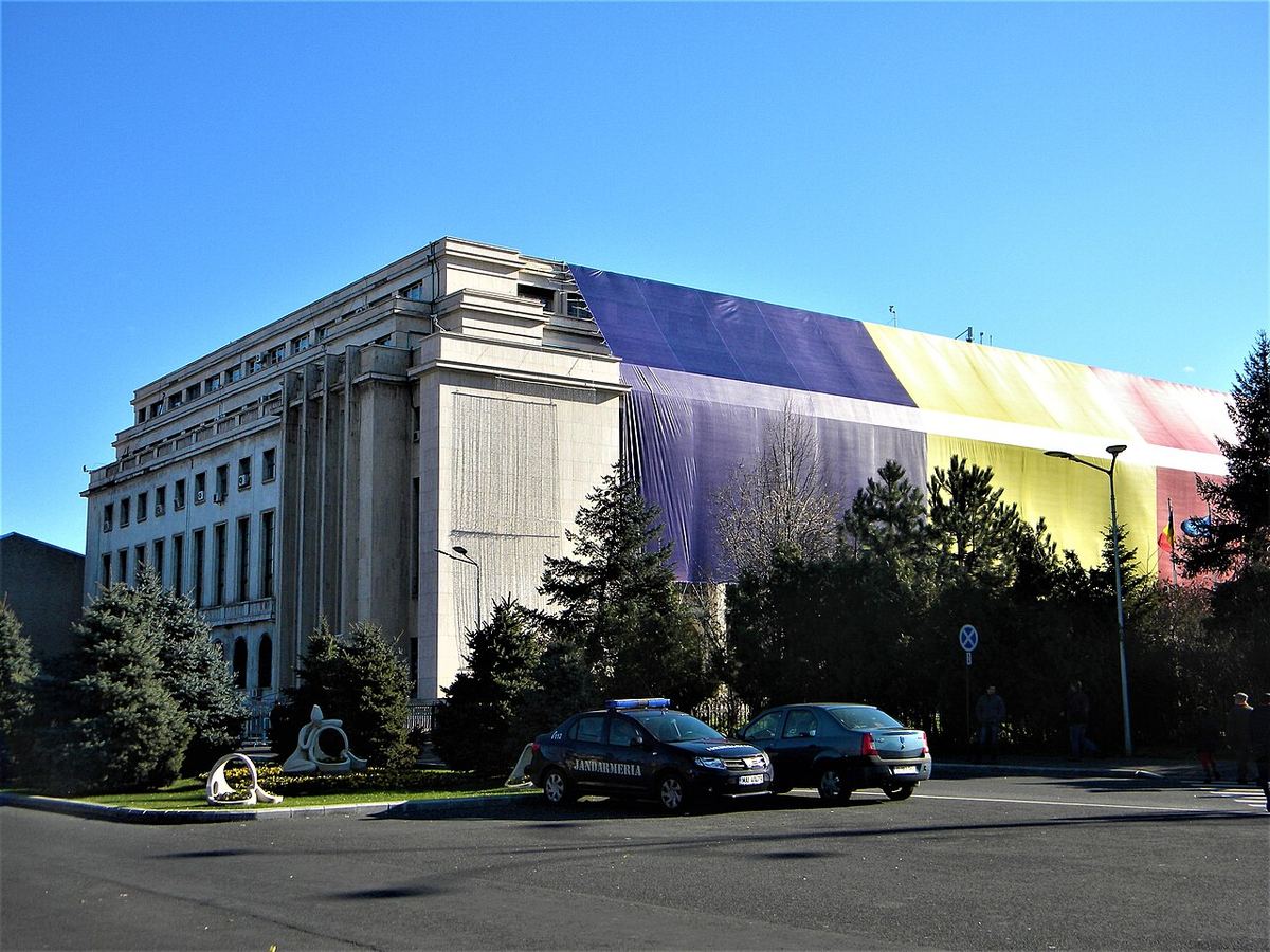 Palatul Victoria, sediul Guvernului României din București, fotografiat din exterior pe timp de zi, cu mașini parcate în față.