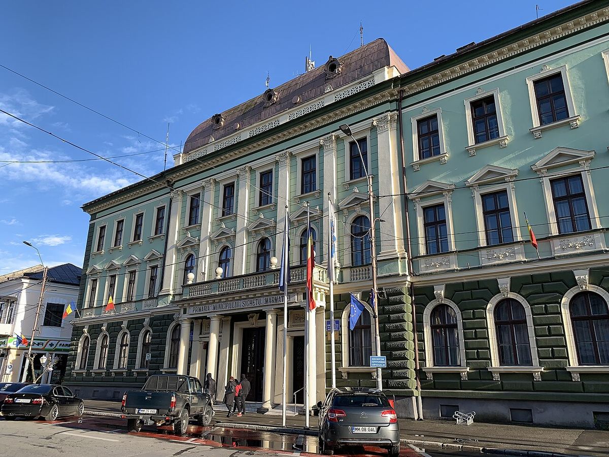 Clădirea Primăriei și a Judecătoriei Sighetu Marmației, cu steaguri, într-o zi senină. Fotografie de arhivă.