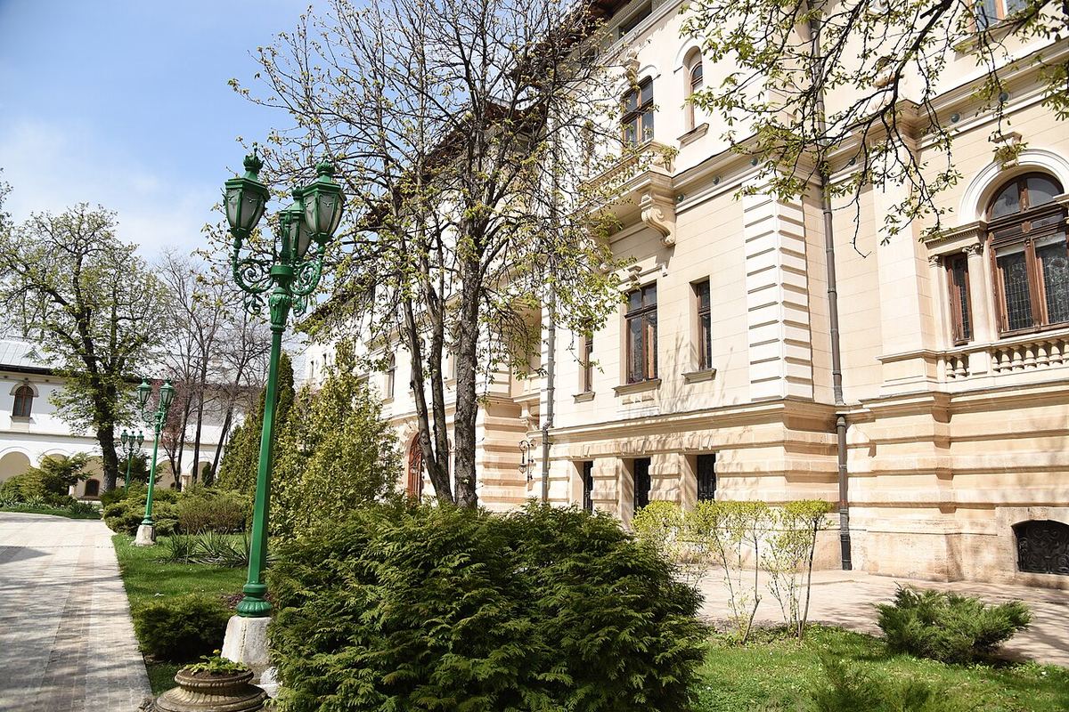 Fațada Palatului Cotroceni din București, sediul Președinției României, fotografiată ziua, cu felinare verzi și arbuști în prim-plan.