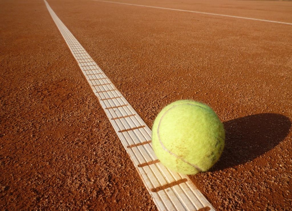 Minge de tenis lângă linia unui teren de zgură