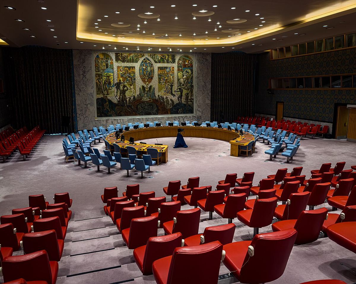 Sala Consiliului de Securitate al ONU din New York, cu masa în formă de potcoavă și scaunele goale, fotografiată din unghi.