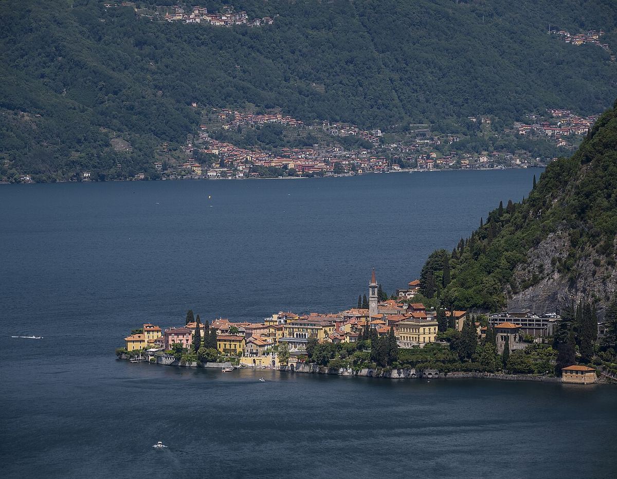 Vedere de pe lac a orașului Varenna, de pe malul lacului Como, cu clădiri istorice și apă liniștită.