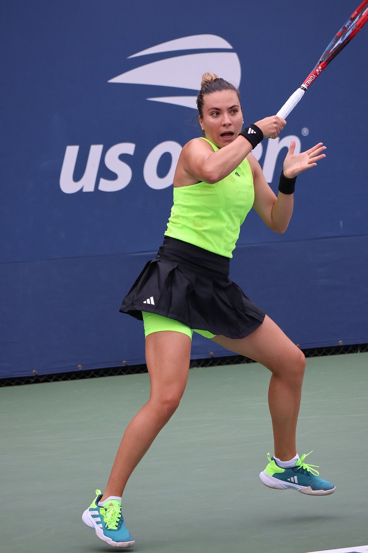 Jucătoare de tenis cu echipament verde neon lovind o minge de forehand pe un teren de tenis, la un turneu US Open (fotografie de arhivă).