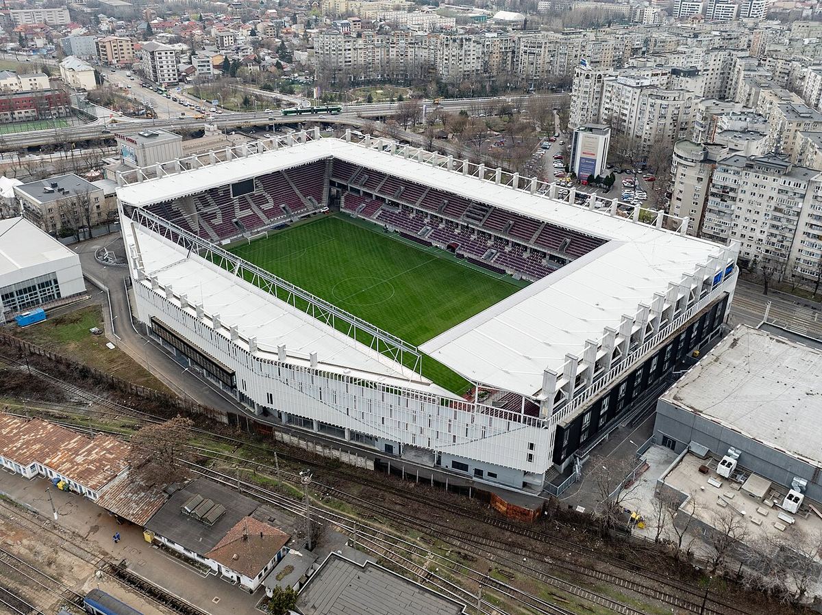 Vedere aeriană a Stadionului Rapid-Giulești din București, cu tribunele vișinii și terenul verde, ilustrativ.