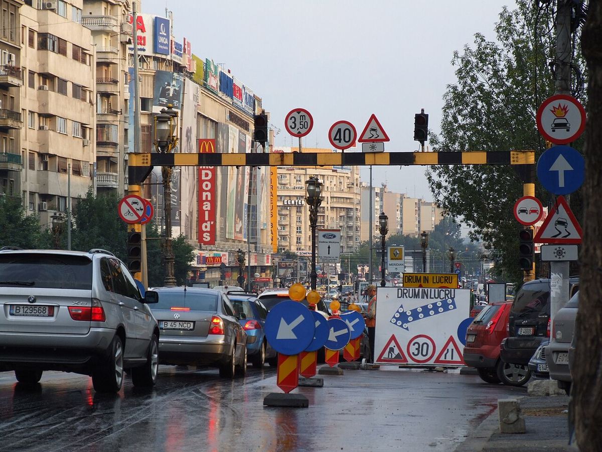Intersecție aglomerată, cu mașini, pe o stradă udă după ploaie