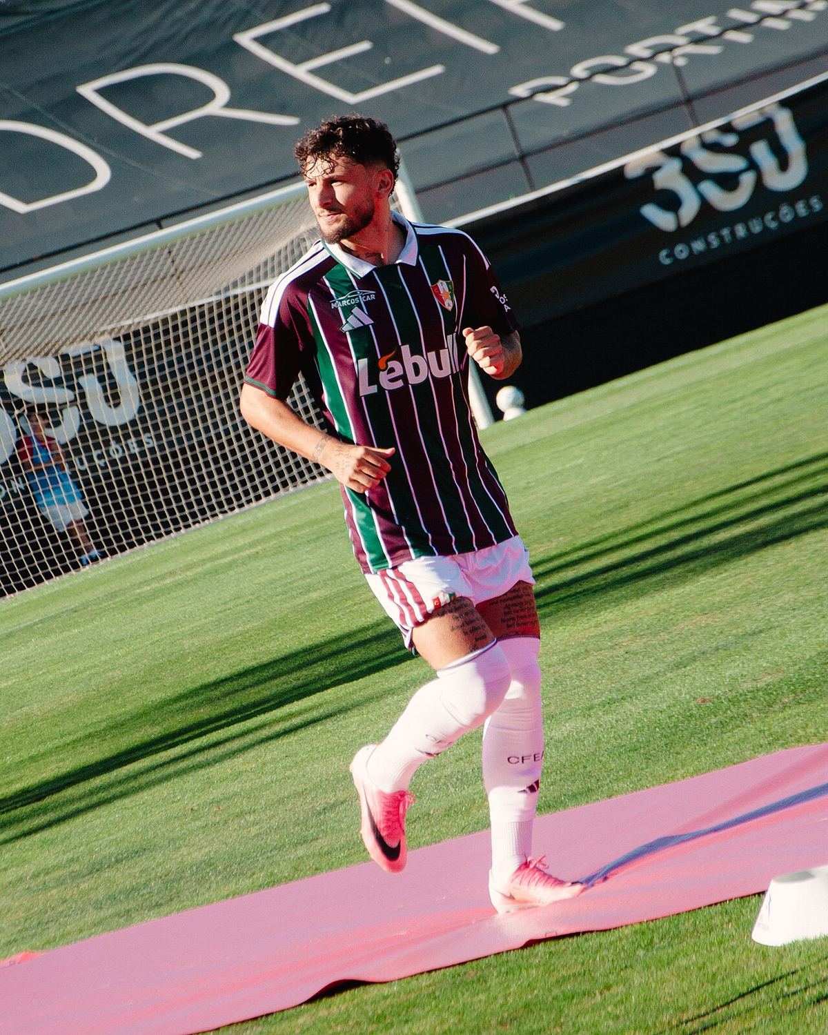 Fotografie a unui fotbalist îmbrăcat în tricoul tricolor al echipei, pe teren de fotbal.