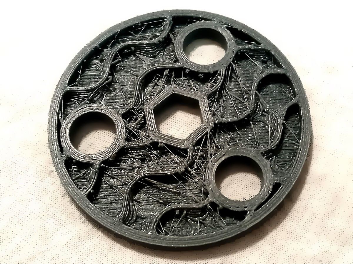 Piesă imprimată 3D cu umplutură din linii duble și fire de filament vizibile între porțiuni (stringing).