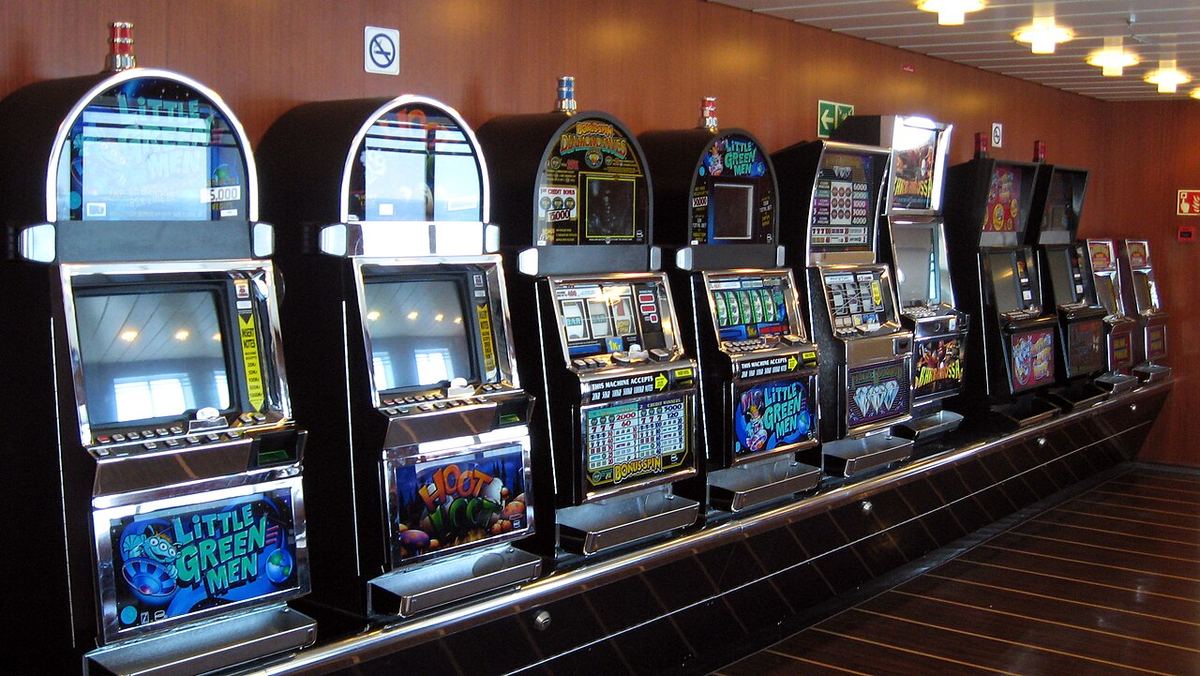 Rânduri de aparate slot-machine, cunoscute și sub denumirea de jocuri cu un braț, în interiorul unei sală de jocuri.