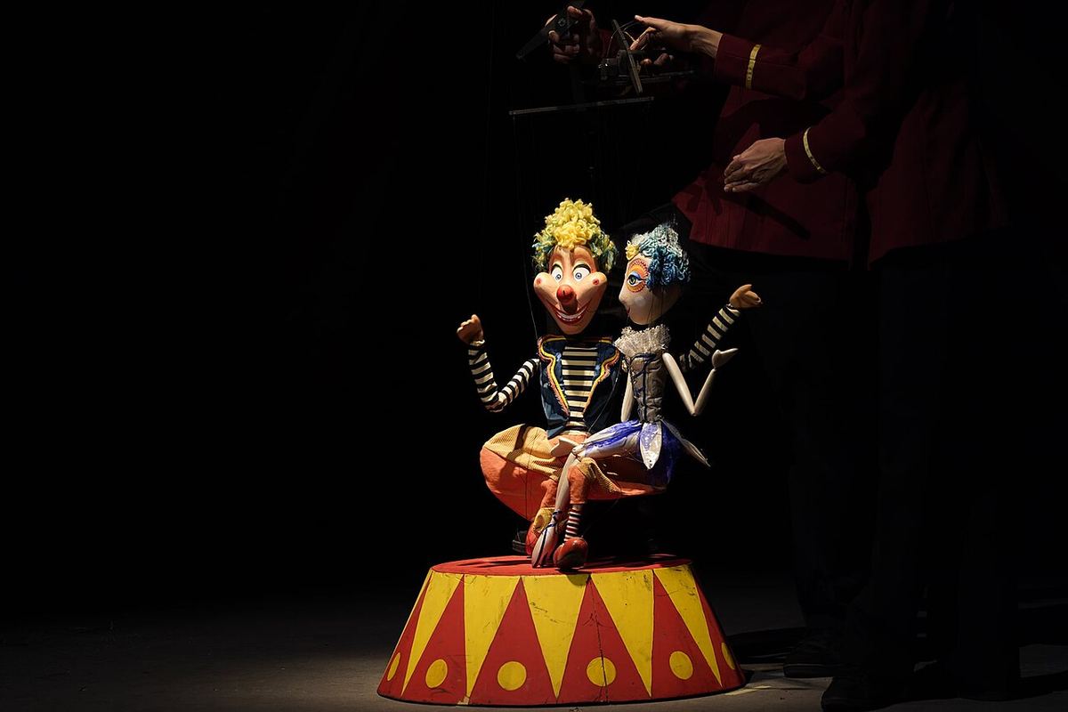 Imagine ilustrativă a unui spectacol de teatru pe scenă, cu interpreți în timpul reprezentației.