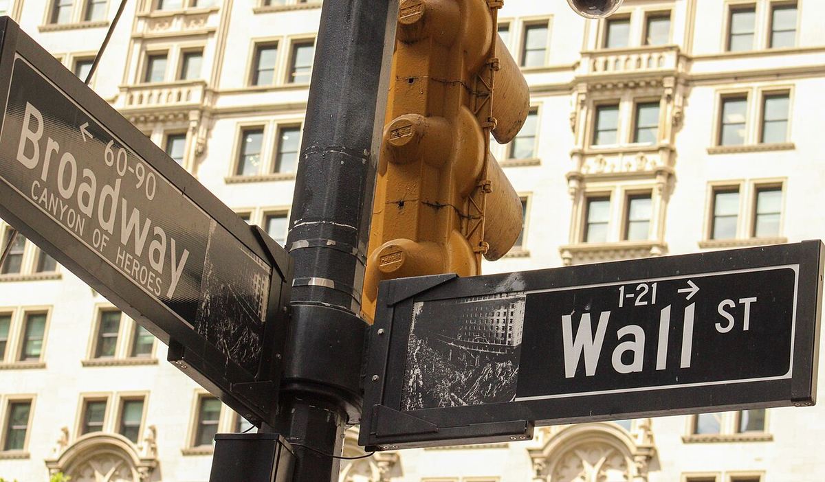 Plăcuțe stradale Broadway și Wall Street din Manhattan, New York, în fața unei clădiri cu fațade clasice.