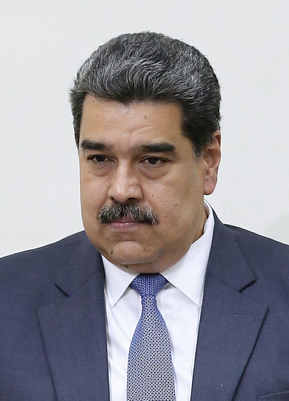 Nicolás Maduro, fotografie de arhivă: bărbat în costum bleumarin, cămașă albă și cravată albastră, pe fundal deschis.