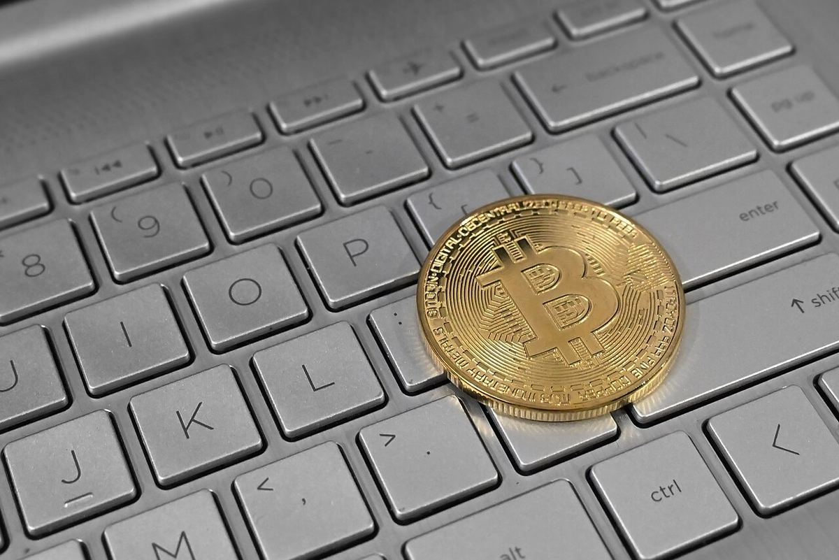 Ilustrație: o monedă Bitcoin așezată pe tastatura unui laptop, simbolizând tranzacțiile cu criptomonede.