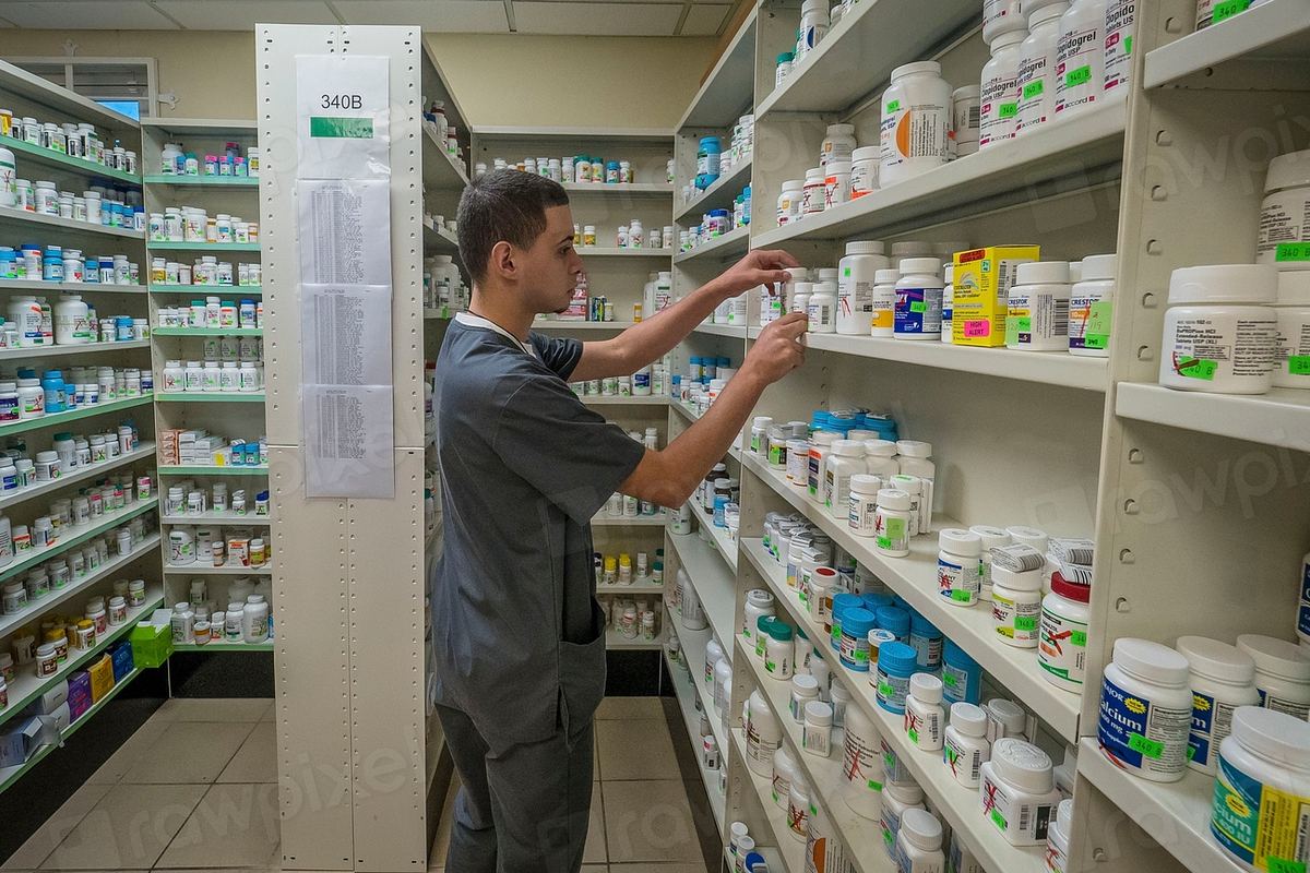 Farmacist care aranjează cutii de medicamente pe rafturi