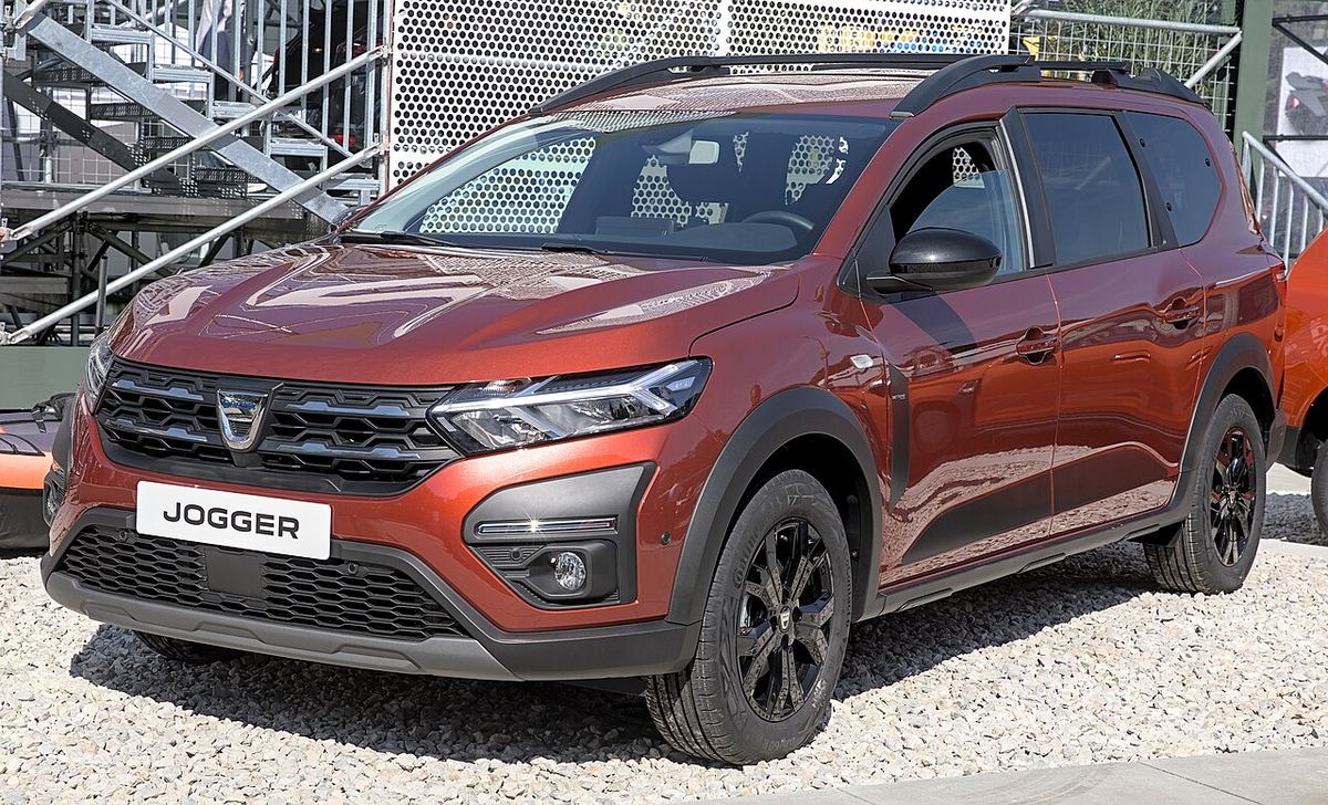 Dacia Jogger portocaliu-cupru, parcat pe pietriș, într-un salon auto. Fotografie de arhivă.