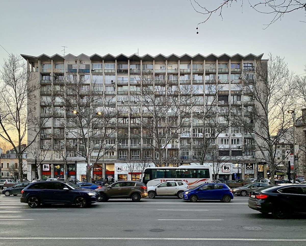 Bloc de apartamente pe Bulevardul Gheorghe Magheru din București, cu multe balcoane, fotografiat ziua, cu trafic în prim-plan.