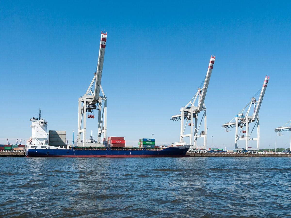 Navă de containere lângă macaralele unui terminal portuar
