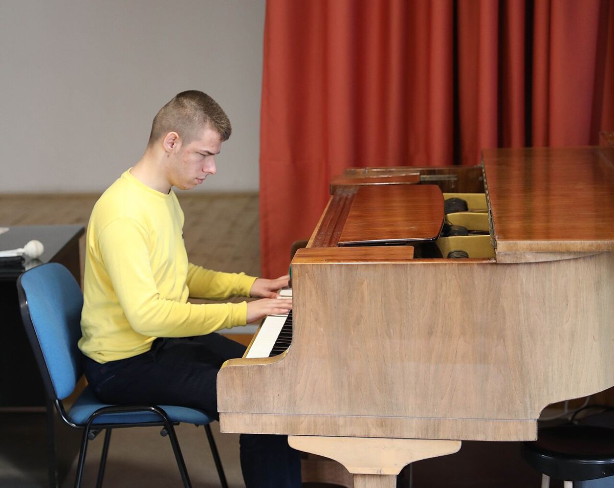 Un pianist cântă la pian într-o sală de concert, în cadrul unui eveniment cultural de schimb.
