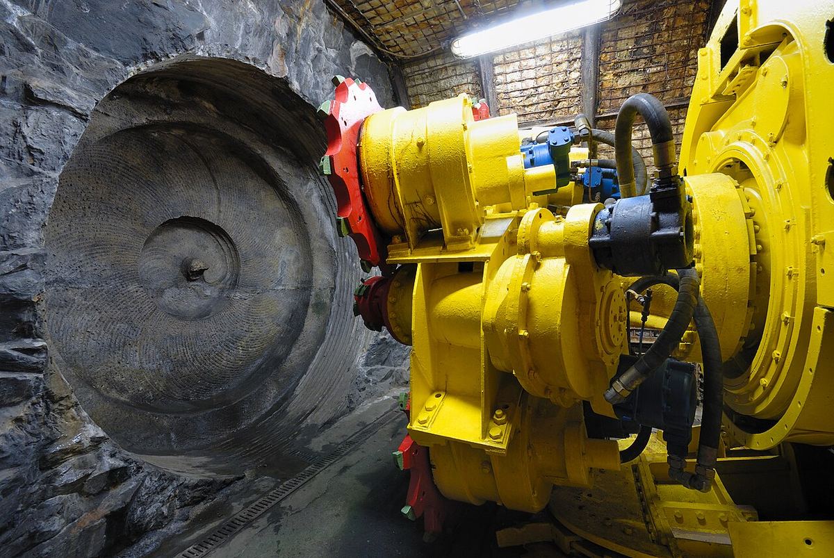 Utilaj de tip TBM (mașină de forat tunele) expus, cu capul de foraj metalic vizibil, ilustrație generică pentru lucrările de tunel.