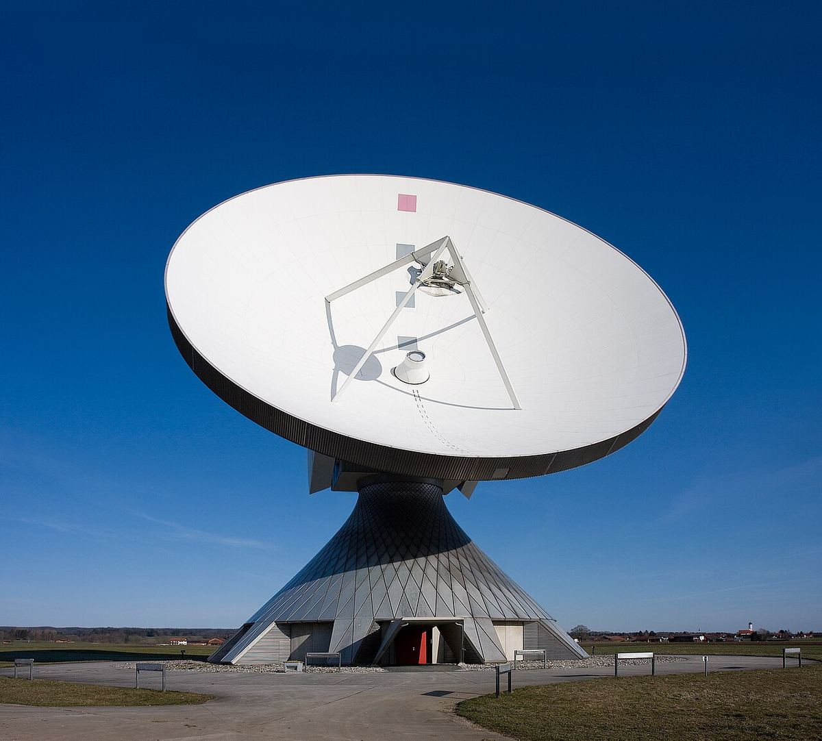 Antenă parabolică mare pentru comunicații prin satelit, orientată spre cer.