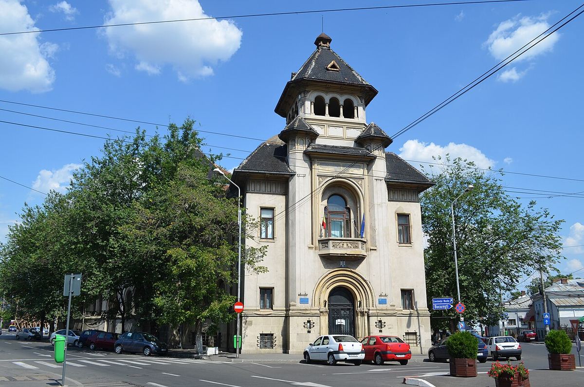 Fațada Tribunalului Județean Prahova din Ploiești, pe o zi însorită, cu mașini parcate în fața clădirii.