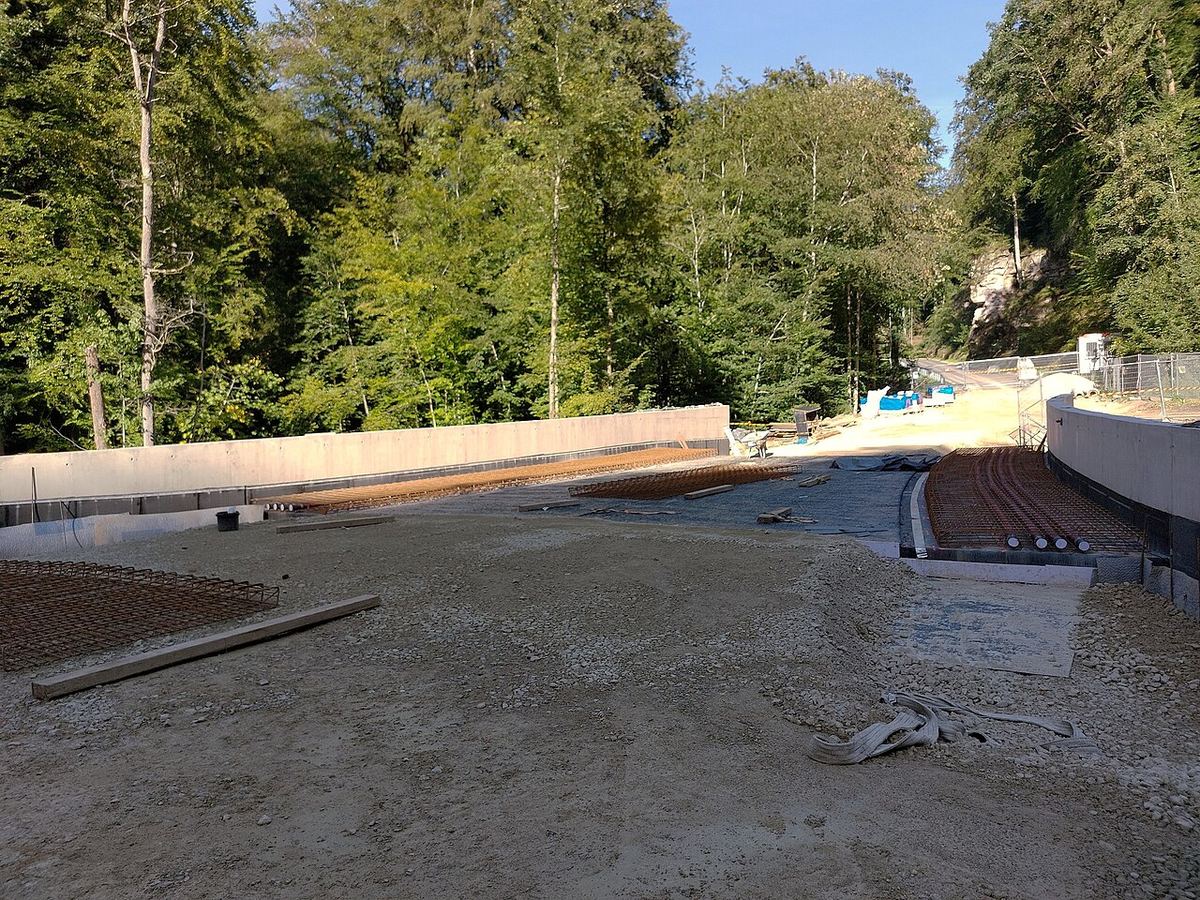 Șantier de construcție a unui pod rutier, cu structuri din beton și utilaje de construcții în zonă.