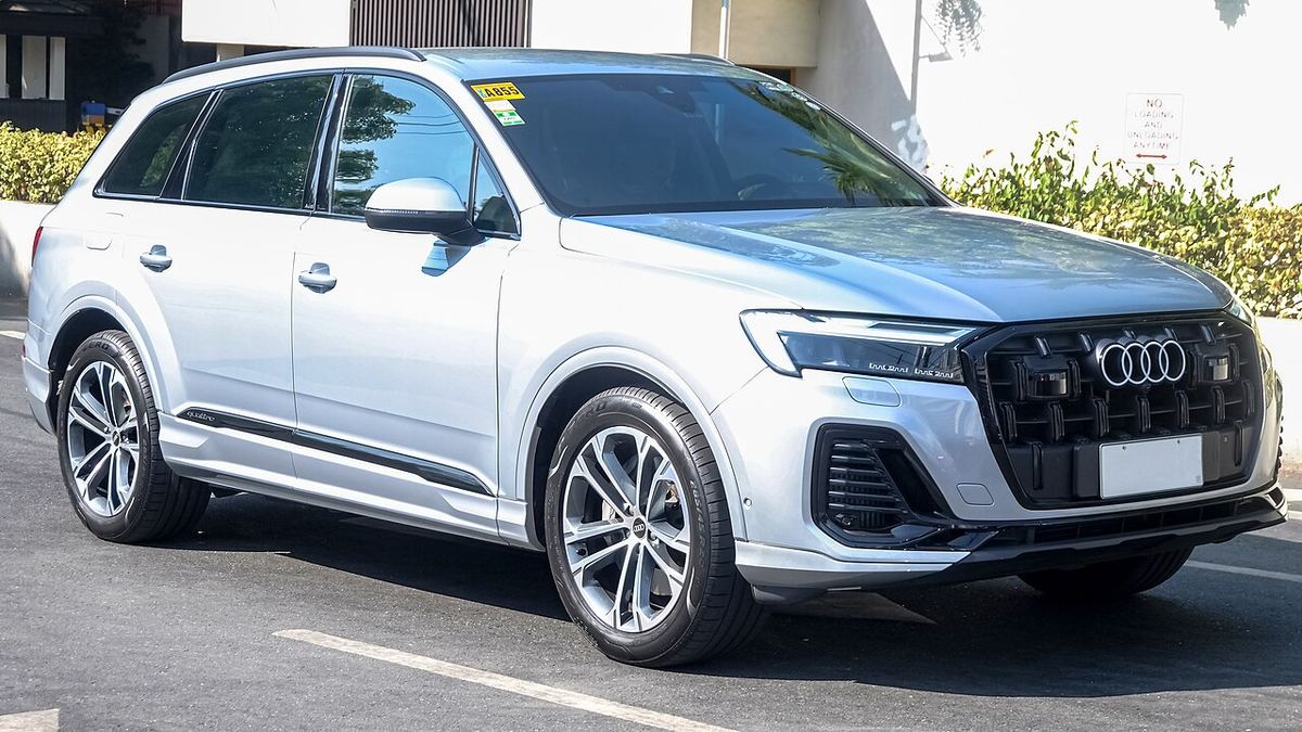 Audi Q7 argintiu parcat pe o stradă, vedere din față a SUV-ului de lux.