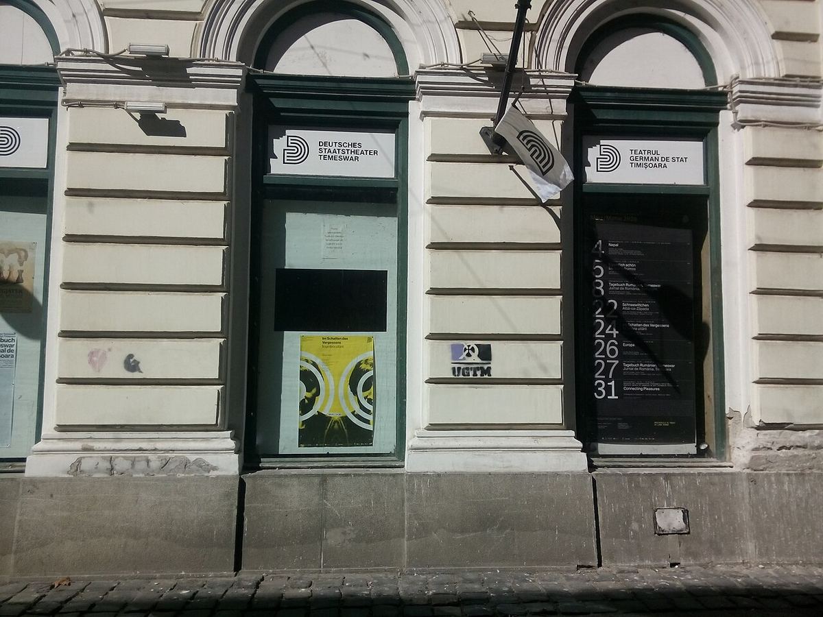 Fațada Teatrului German de Stat Timișoara, cu inscripții în germană și română pe ferestre și pe ușa de intrare.