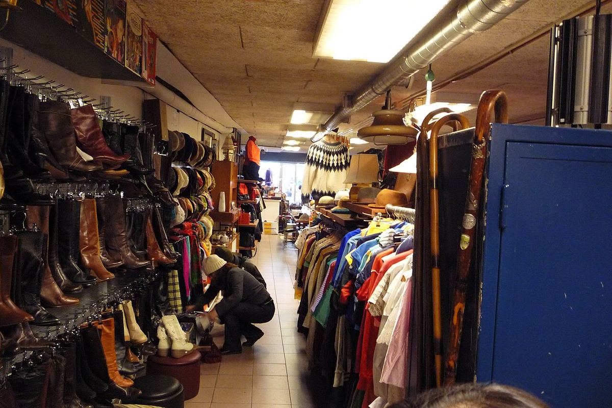 Persoană care caută printre haine vintage second-hand expuse pentru vânzare