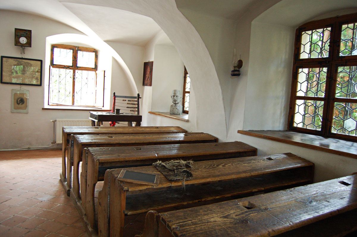 Sală de clasă cu bănci de lemn