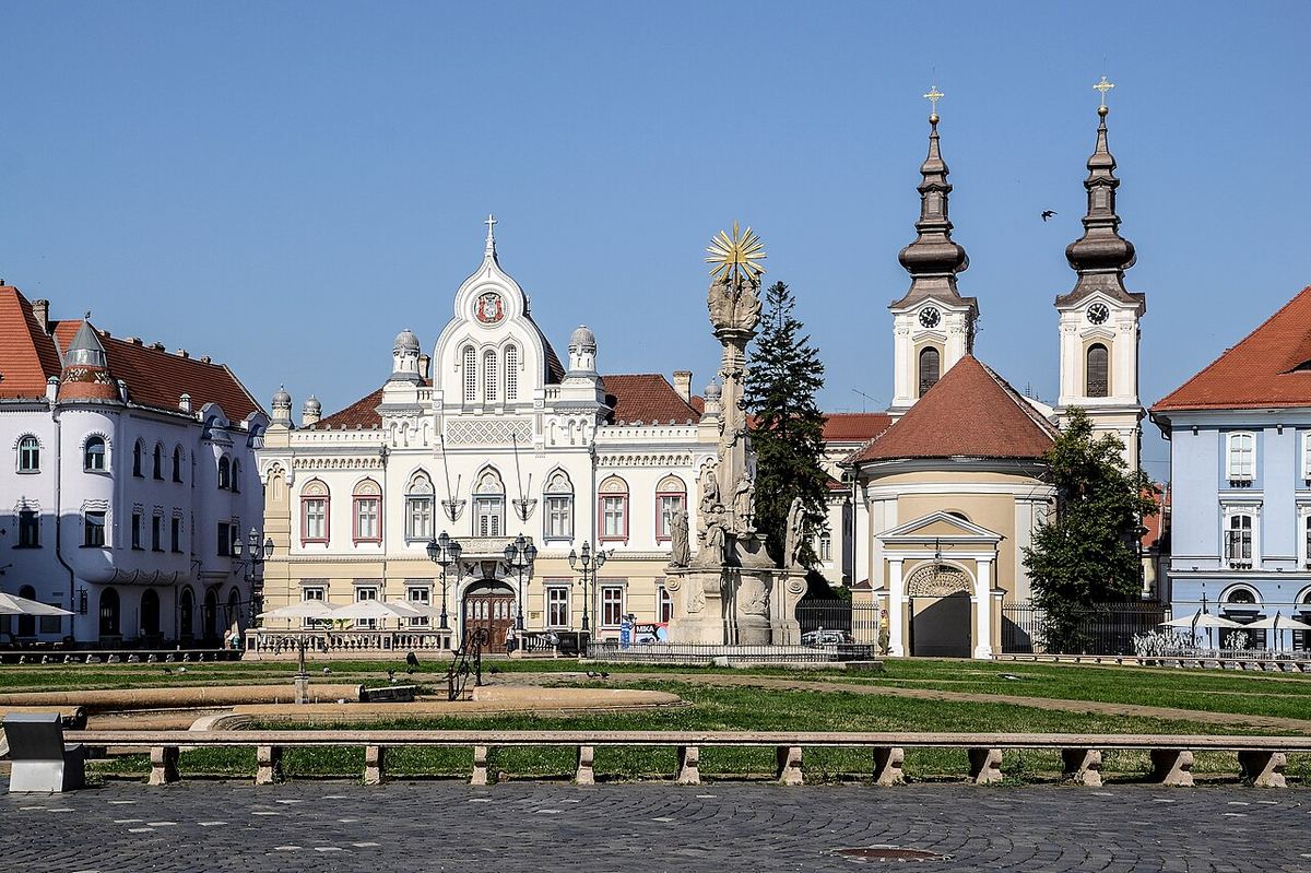Vedere a unei piețe publice urbane, cu clădiri de-a lungul laturilor și spațiu pietonal amenajat.